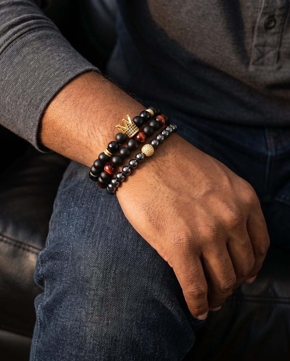 Man's wrist wearing a stack of Onyx Crown, Ember Onyx and Gunmetal and Gold bracelets
