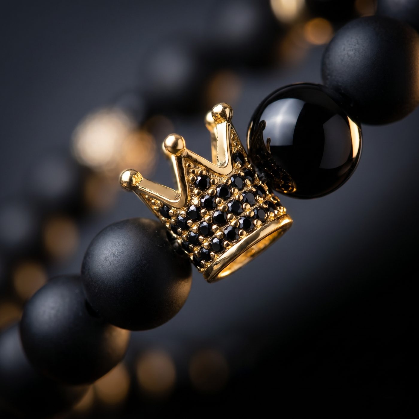 Close-up of the gold micro-pavé crown charm between onyx beads
